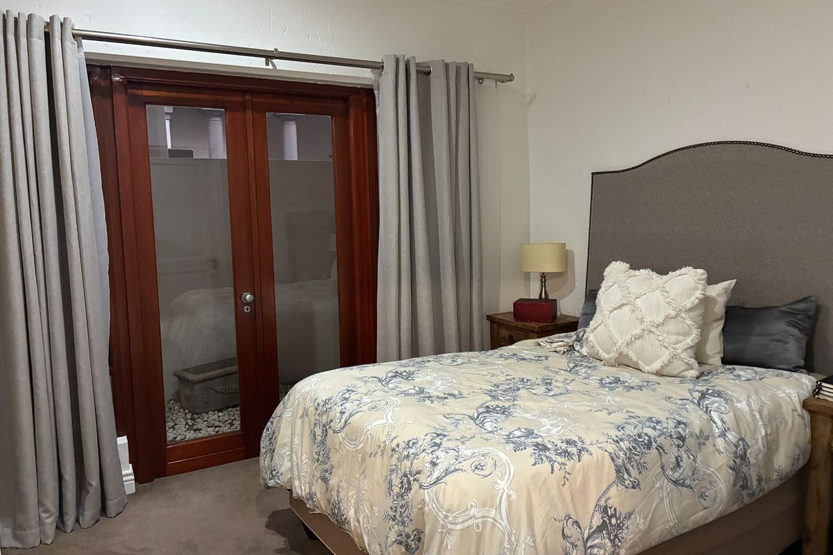 A bedroom featuring carpeted flooring and timber-framed glass double doors leading to an outdoor area.