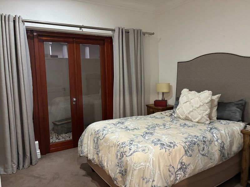 A bedroom featuring carpeted flooring and timber-framed glass double doors leading to an outdoor area.