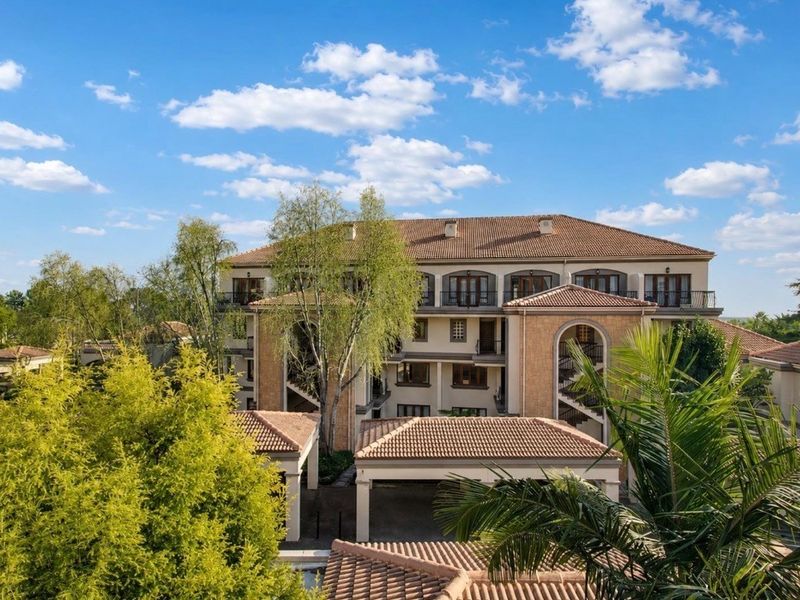 An elevated view of the apartment complex featuring Mediterranean-style architecture with terracotta tiled roofs and arched structural elements.