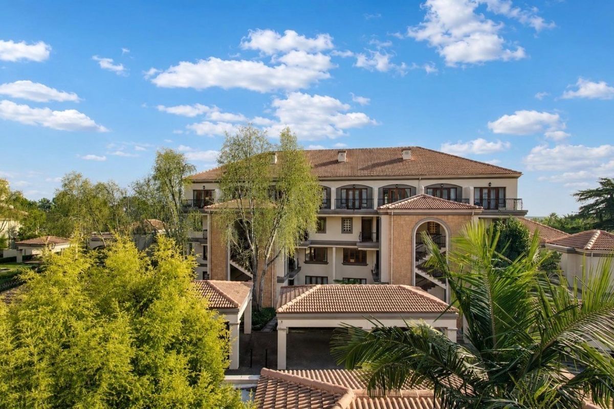 An elevated view of the apartment complex featuring Mediterranean-style architecture with terracotta tiled roofs and arched structural elements.