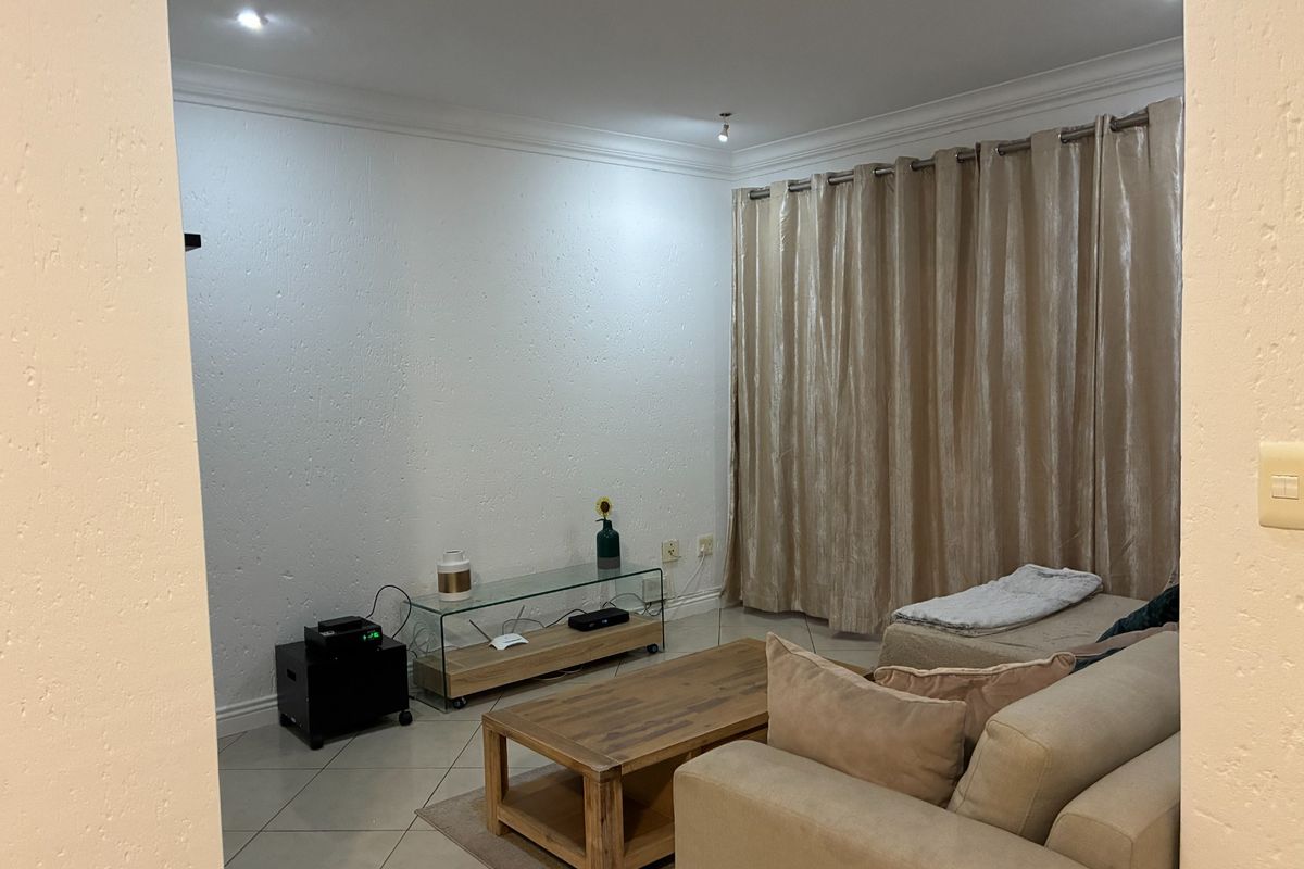 A comfortable living room featuring tiled flooring, recessed ceiling lighting, and floor-to-ceiling curtains.
