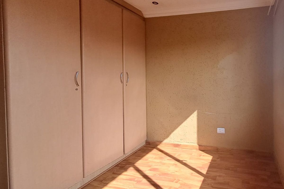 A bedroom featuring built-in cupboards, textured wall finishes, and wood-look flooring with recessed ceiling lighting.