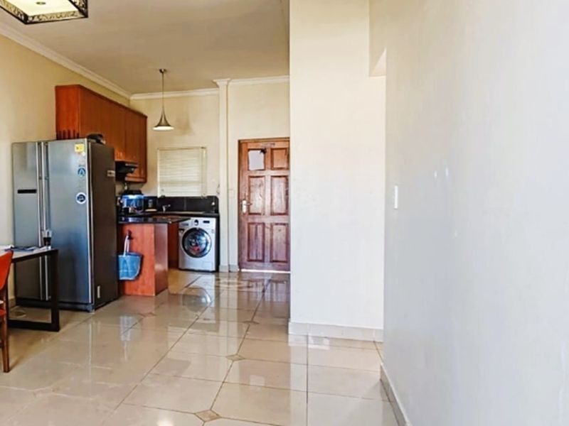 Open-plan living area featuring tiled flooring and a functional kitchen space with built-in cabinetry and integrated laundry plumbing.