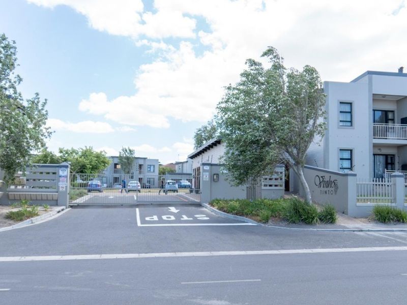 Front entrance view of Vinhos Tinto apartment complex featuring secure gated access, paved driveway, and multi-story residential units with balconies.