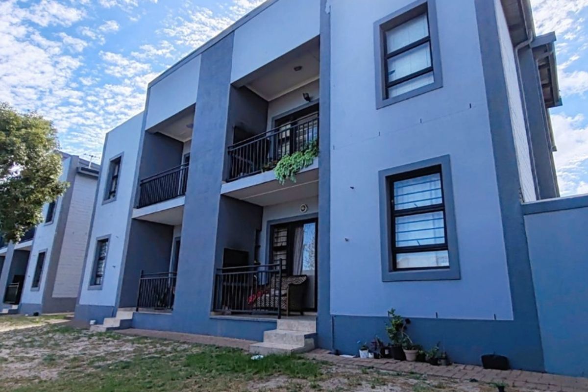 A multi-story apartment building exterior featuring private balconies with metal railings, sliding glass doors, and security bars on the windows.