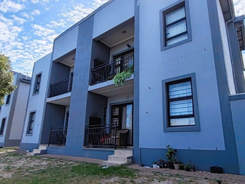 A multi-story apartment building exterior featuring private balconies with metal railings, sliding glass doors, and security bars on the windows.