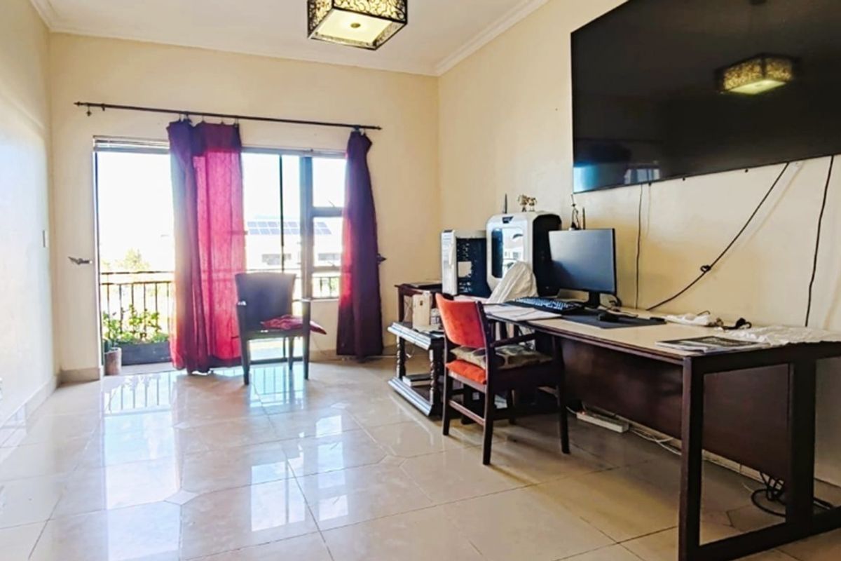A living room featuring tiled flooring and a sliding glass door providing access to a balcony, offering natural light and functional living space.