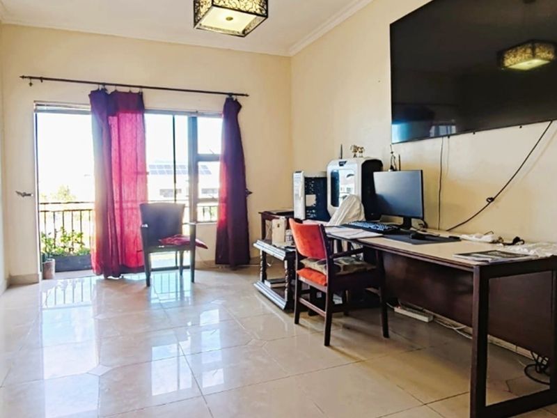 A living room featuring tiled flooring and a sliding glass door providing access to a balcony, offering natural light and functional living space.