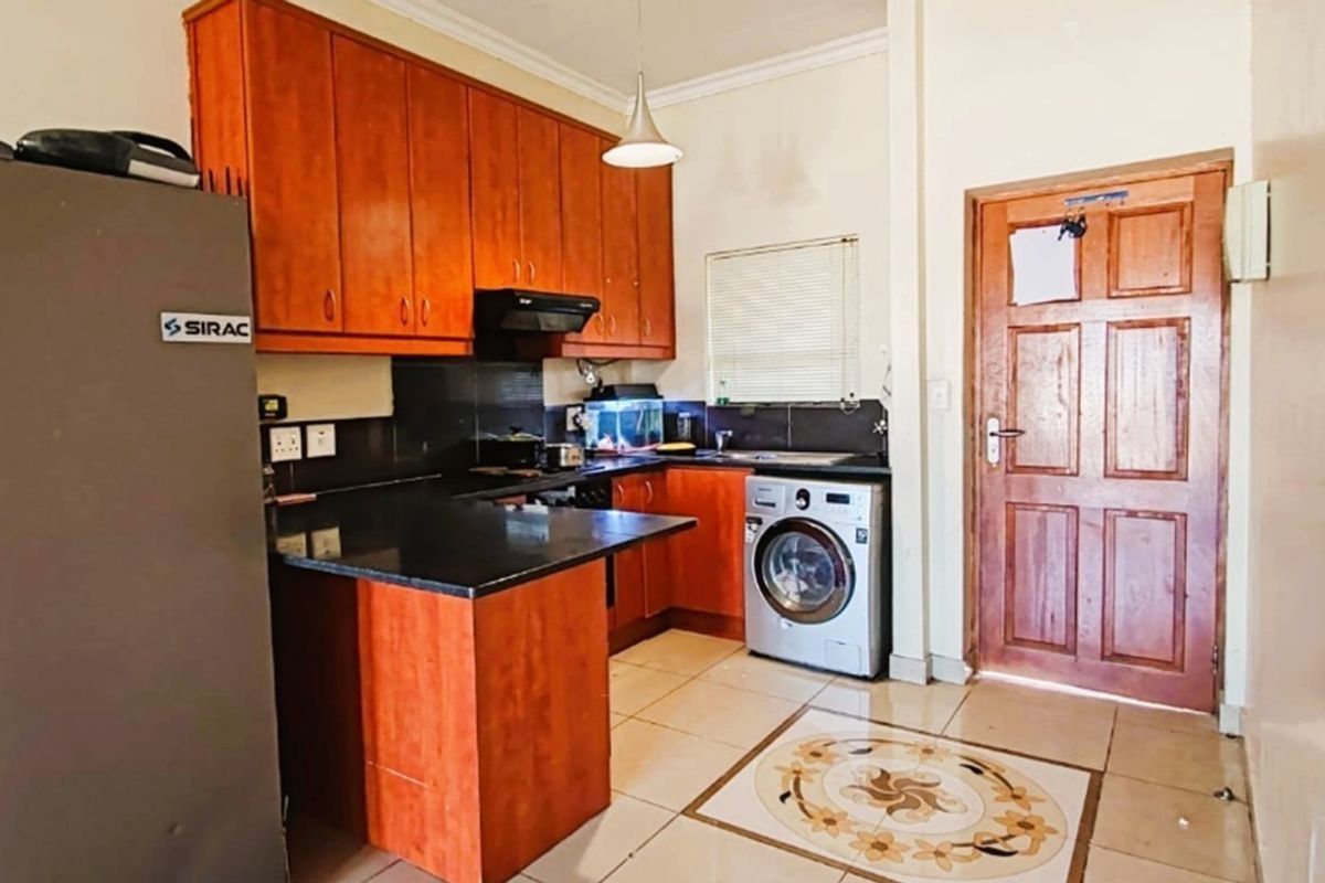 A functional kitchen featuring wooden cabinetry, granite countertops, and tiled flooring, providing a practical workspace with integrated appliance connections.