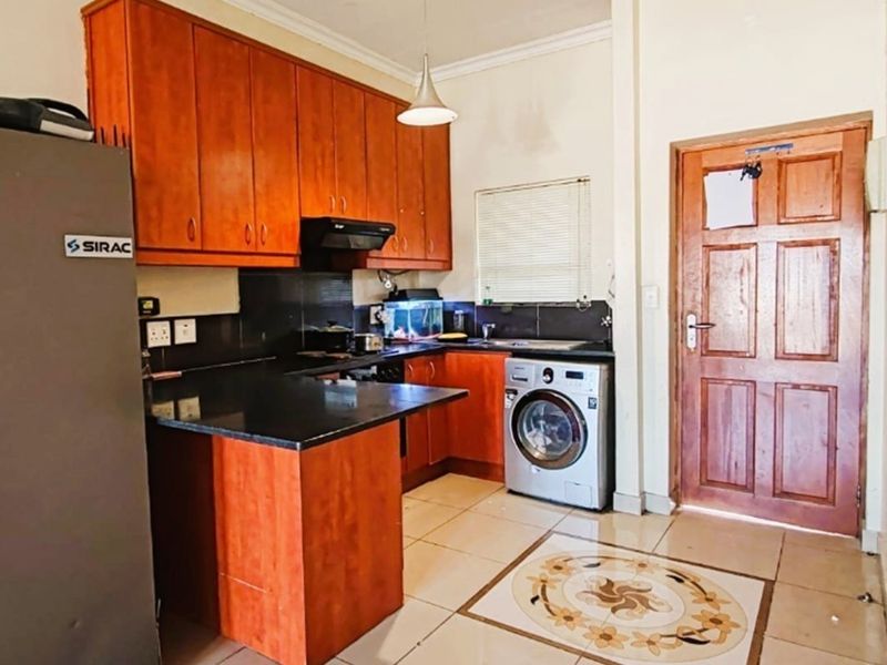 A functional kitchen featuring wooden cabinetry, granite countertops, and tiled flooring, providing a practical workspace with integrated appliance connections.