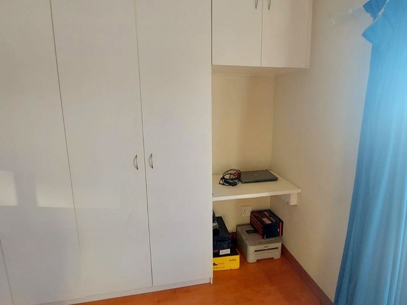 Bedroom featuring built-in cupboards and a compact integrated desk area with laminate flooring.