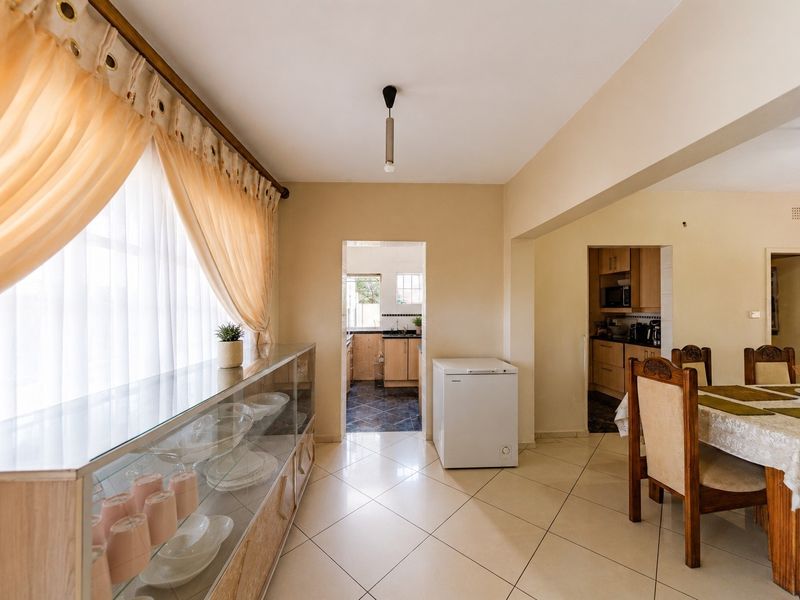 Open plan living and dining area featuring tiled flooring and a seamless transition into the kitchen and scullery spaces.