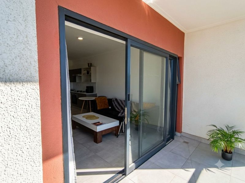 A modern balcony featuring tiled flooring and a large sliding glass door providing access to the interior living area.