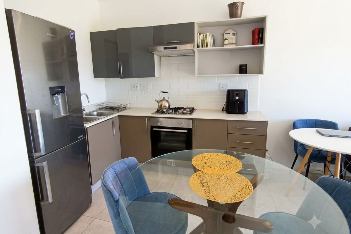 Modern kitchen featuring two-tone cabinetry, stone countertops, subway tile backsplash, and integrated gas hob with extractor fan.