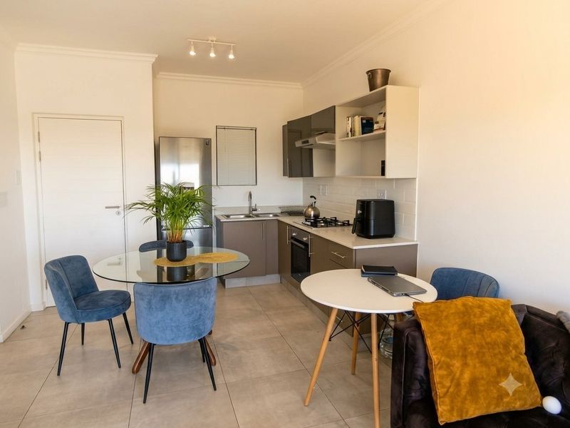 An open-plan living and kitchen area featuring modern cabinetry, a gas hob, built-in oven, and neutral tiled flooring throughout.