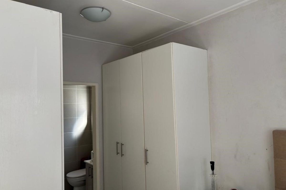 A bedroom featuring built-in white cabinetry and a view into an adjacent tiled bathroom.