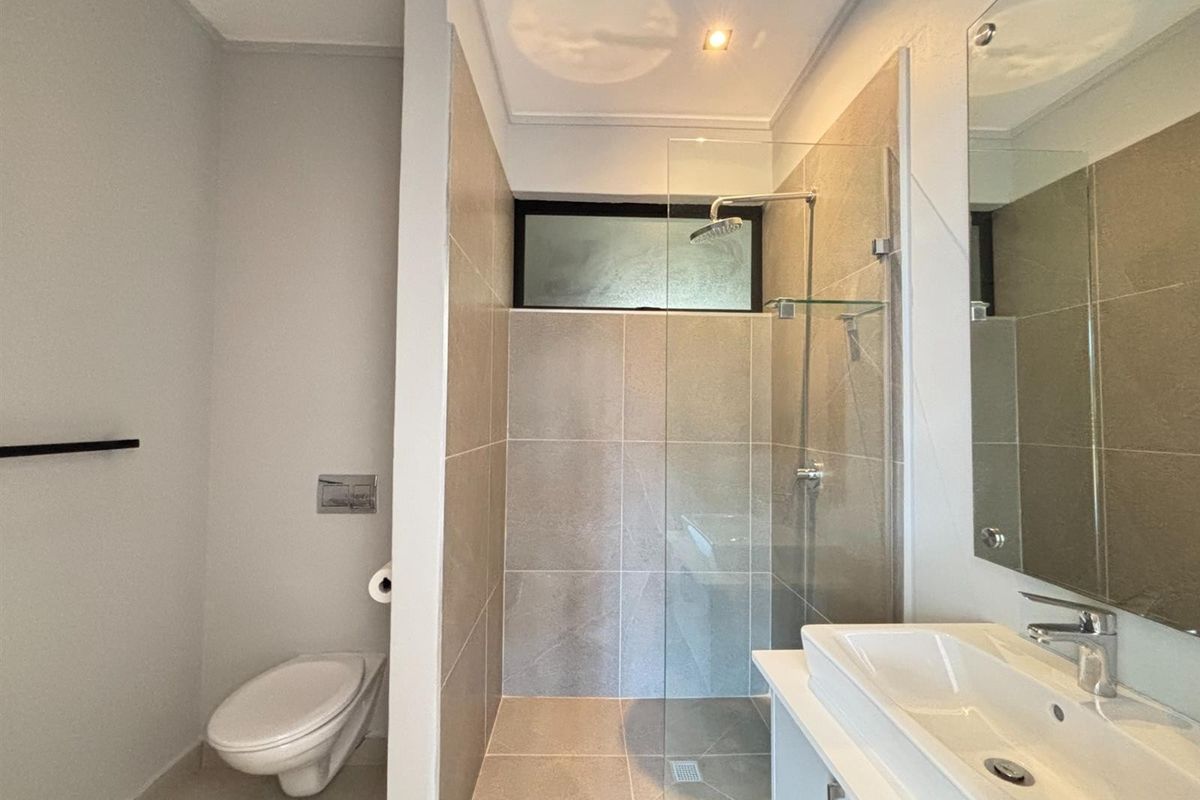Modern bathroom featuring a glass-enclosed walk-in shower, wall-mounted toilet, and a sleek vanity with a basin.