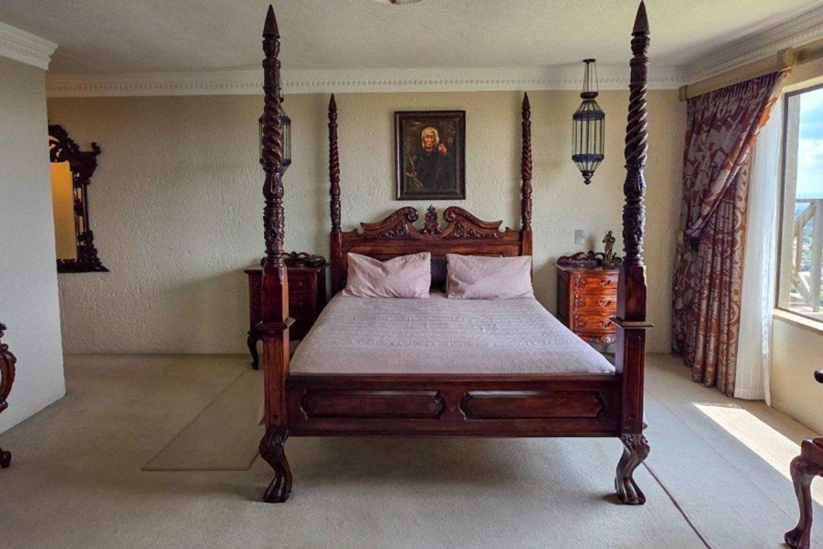 Spacious bedroom featuring large windows with panoramic views, neutral carpeting, and decorative crown molding.