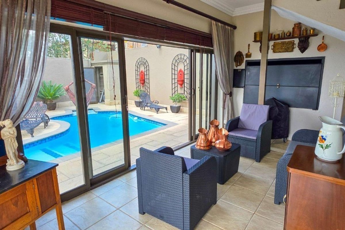 A bright living area featuring large sliding glass doors that open directly onto a private swimming pool and patio space.