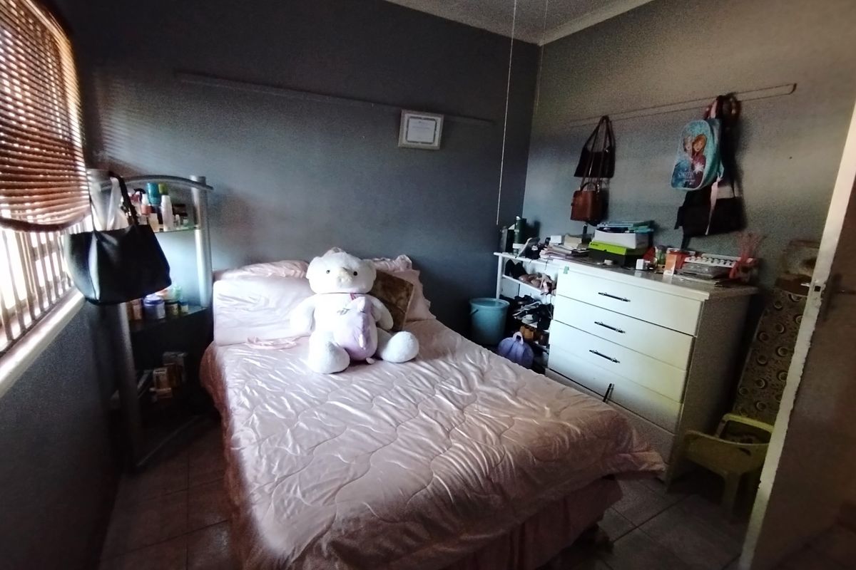 A bedroom featuring tiled flooring and dark-toned walls, providing a functional sleeping space with natural light from the side window.