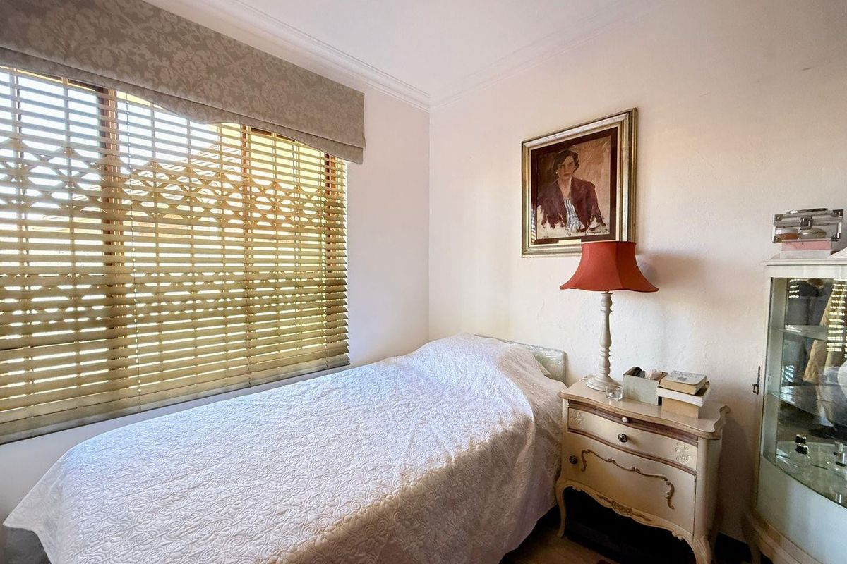 A cozy bedroom featuring a ceiling fan, decorative cornice, and window blinds, offering a comfortable and functional living space.