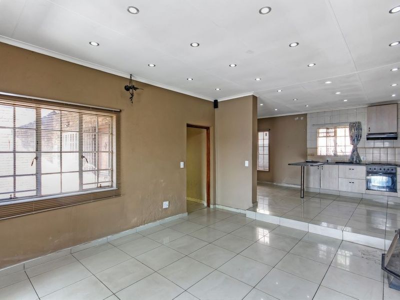 Spacious open-plan living and kitchen area featuring tiled flooring, recessed lighting, a built-in oven, and a fireplace, offering a versatile layout for modern living.