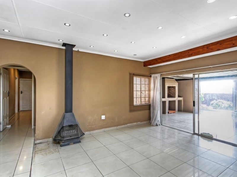 Spacious living area featuring tiled floors, a modern freestanding fireplace, recessed lighting, and sliding doors leading to an outdoor patio area.