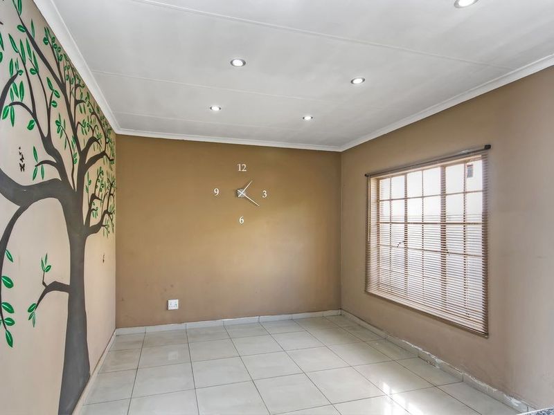 An empty living area featuring tiled flooring, recessed downlighting, and a decorative wall mural, ready for personalization.
