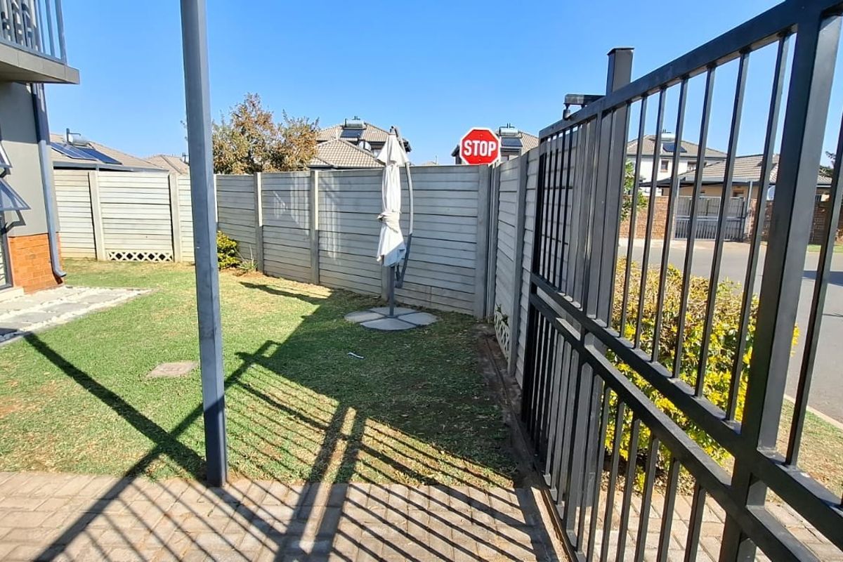 A private rear garden area featuring a paved patio, lawn, and secure perimeter walling with direct access to the home via a sliding door.
