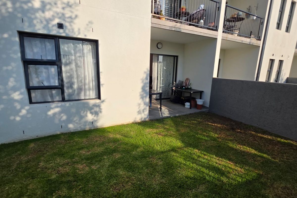 Rear view of the unit featuring a private garden, a covered patio area, and access via a sliding glass door.