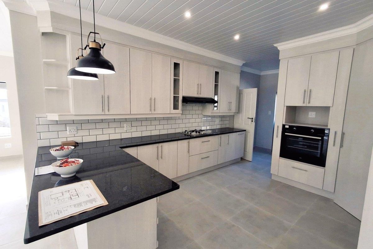 Modern kitchen featuring light wood cabinetry, contrasting black granite countertops, subway tile backsplash, built-in oven, and a tongue-and-groove ceiling with recessed lighting.