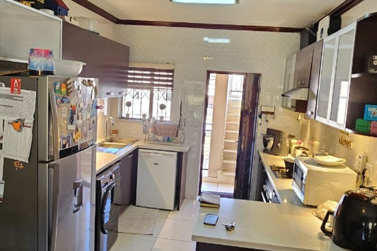 A functional kitchen featuring tiled flooring, built-in cabinetry, stone-look countertops, and a breakfast bar area with direct access to an exterior space.