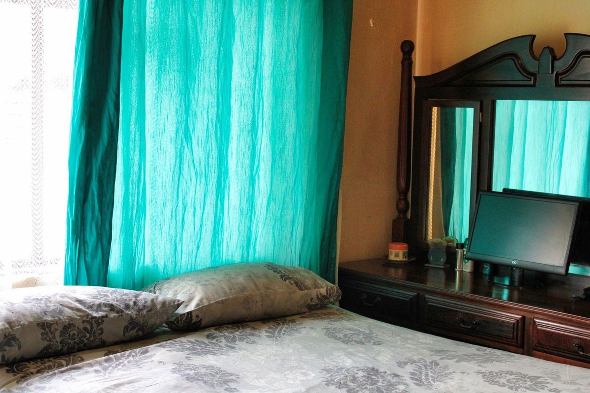 A bedroom interior featuring a window with curtains and space for bedroom furniture.
