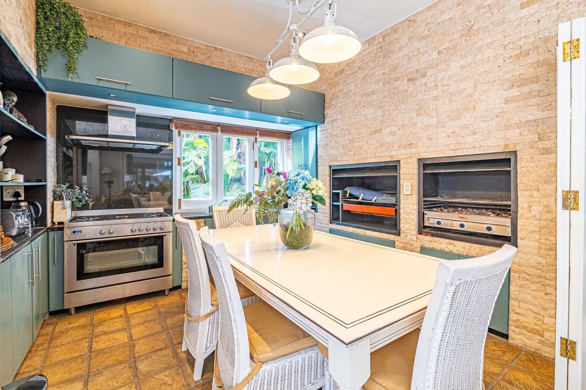 A functional kitchen and dining area featuring built-in braai units, stone-clad feature wall, gas stove, and ample cabinetry.
