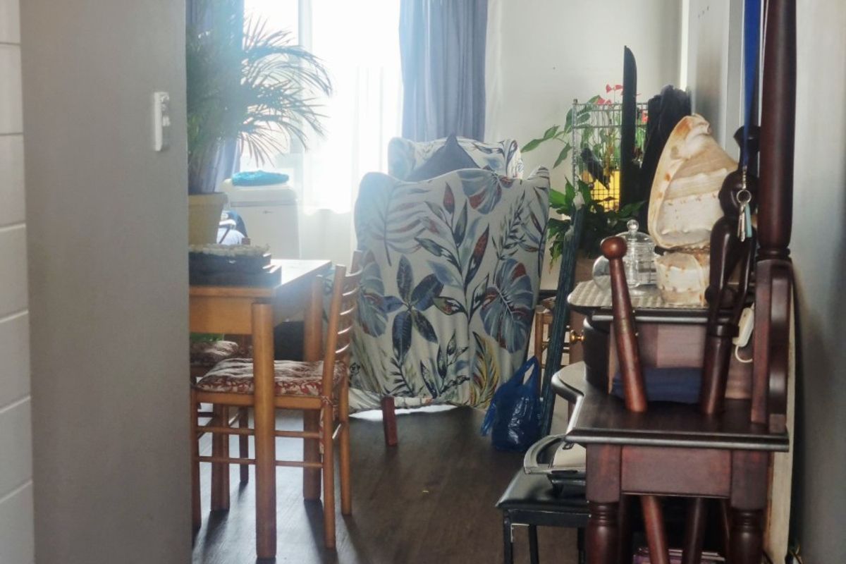 A view from a hallway into a living area featuring laminate flooring and natural light from a sliding glass door.