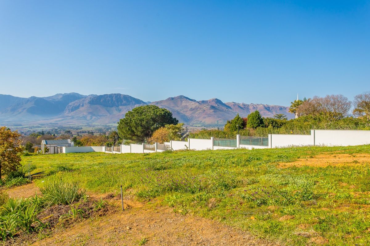 A vacant residential plot featuring established perimeter walling, electric fencing, and panoramic mountain views.