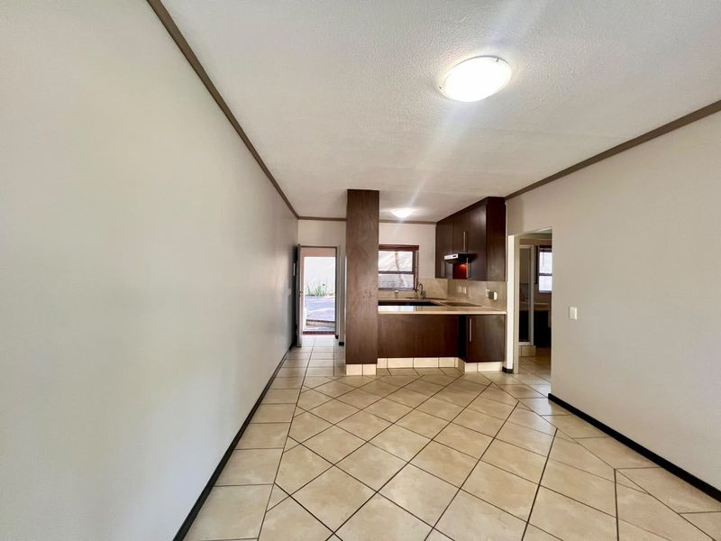 An open-plan living and kitchen area featuring tiled flooring, dark wood-toned cabinetry, and direct access to an outdoor space.