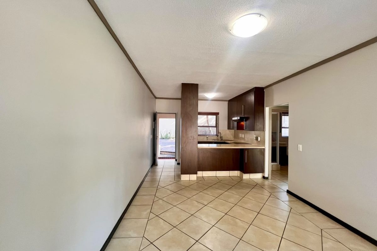 An open-plan living and kitchen area featuring tiled flooring, dark wood-toned cabinetry, and direct access to an outdoor space.