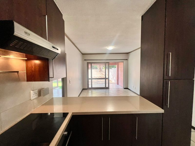 Open-plan kitchen and living area featuring dark wood cabinetry, stone countertops, and direct access to a covered patio through sliding glass doors.