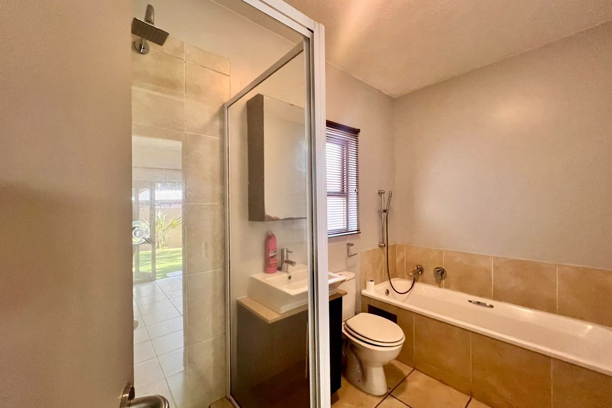 A functional bathroom featuring a separate shower enclosure, bathtub, built-in vanity with basin, and tiled finishes throughout.