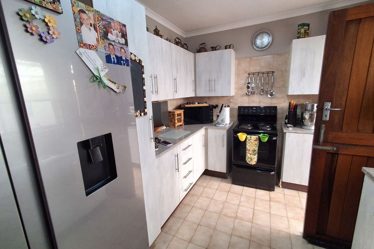 A functional kitchen featuring light-toned cabinetry, tiled flooring, and a built-in stove, offering a practical layout for daily meal preparation.