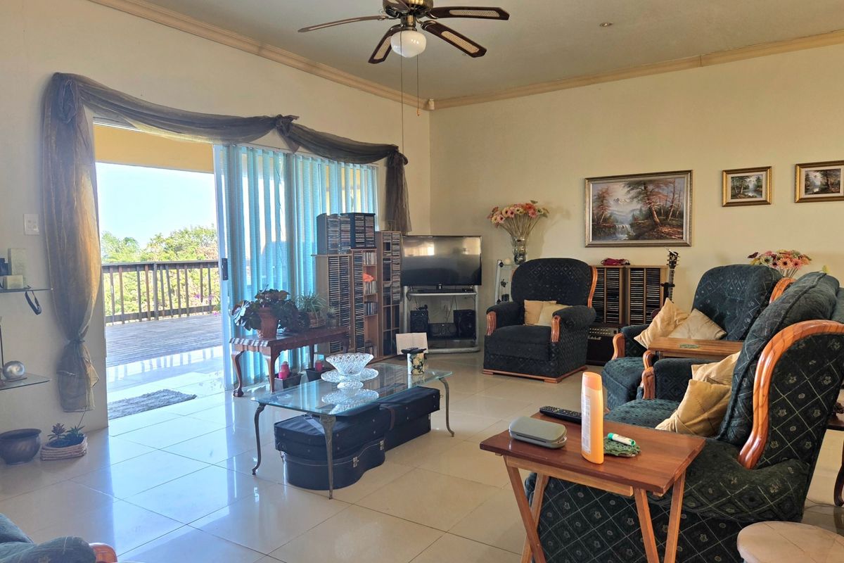 Spacious living room featuring large sliding glass doors that open onto an outdoor deck, complemented by tiled flooring and a ceiling fan.