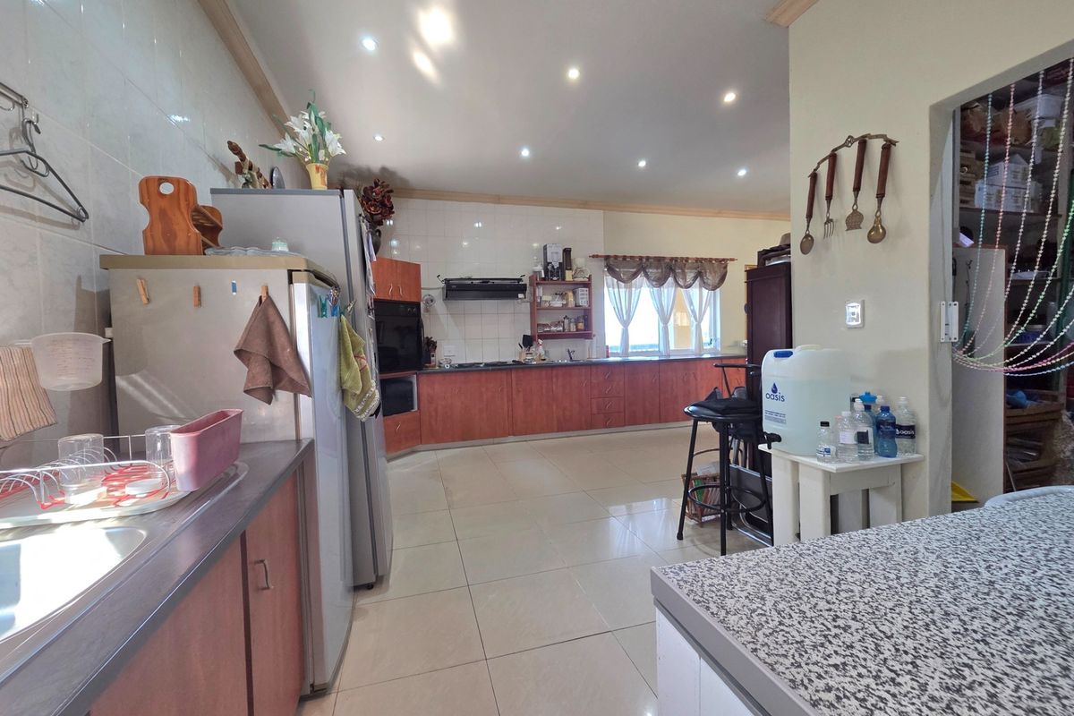 Spacious kitchen featuring extensive wooden cabinetry, built-in oven, extractor fan, and tiled flooring, offering a functional layout with ample counter space.