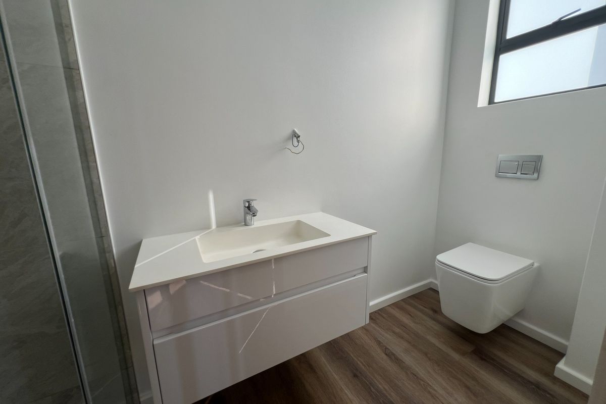 Modern bathroom featuring a wall-mounted vanity with integrated basin, a sleek wall-hung toilet, and a glass-enclosed shower with contemporary finishes.