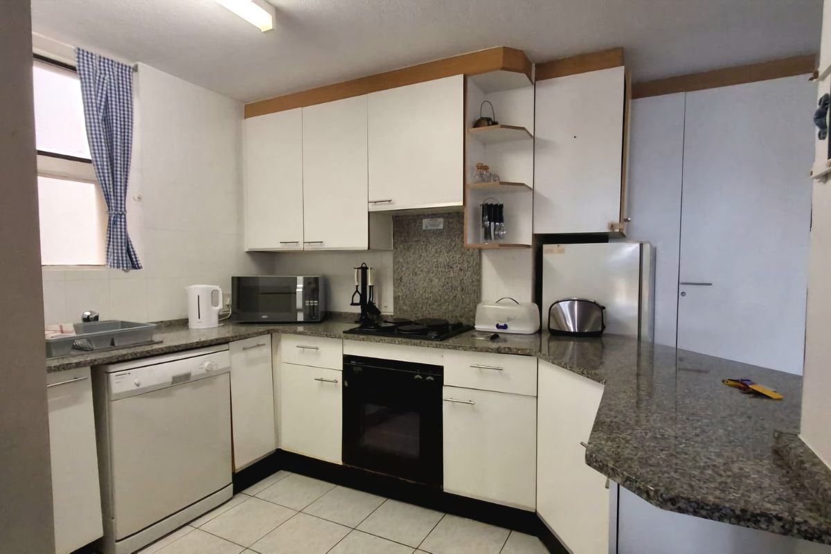 A functional kitchen featuring granite countertops, white cabinetry, a built-in oven, hob, and integrated dishwasher space.