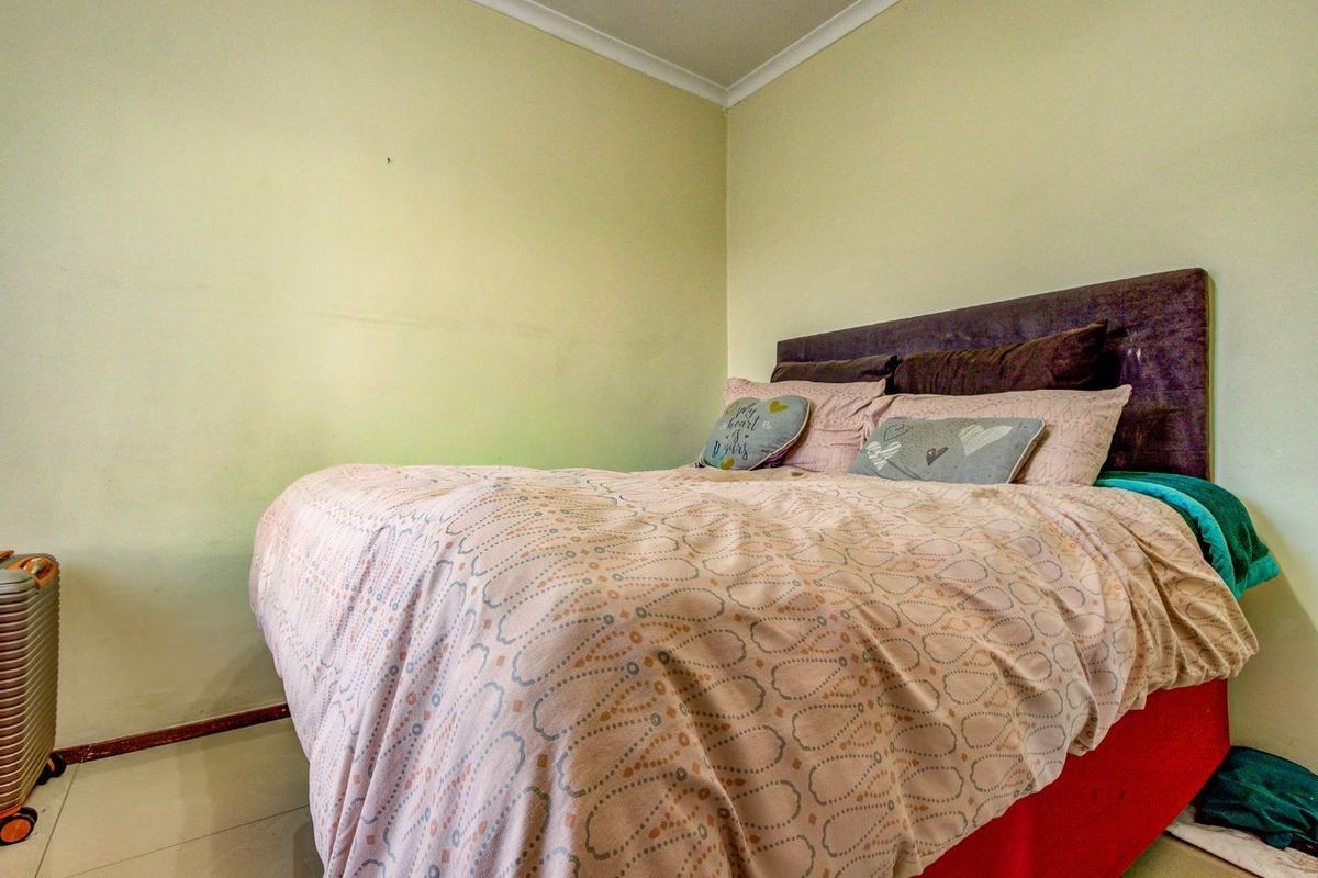 A functional bedroom featuring tiled flooring and neutral wall finishes, providing a simple and comfortable sleeping space.