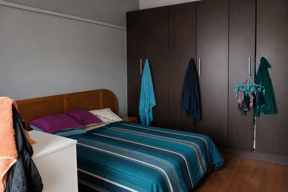 A bedroom featuring dark wood built-in wardrobes and timber flooring, providing ample storage space.