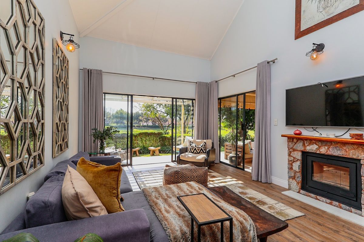 Spacious living room featuring a vaulted ceiling, stone fireplace, and large sliding glass doors providing seamless access to the outdoor patio and garden.