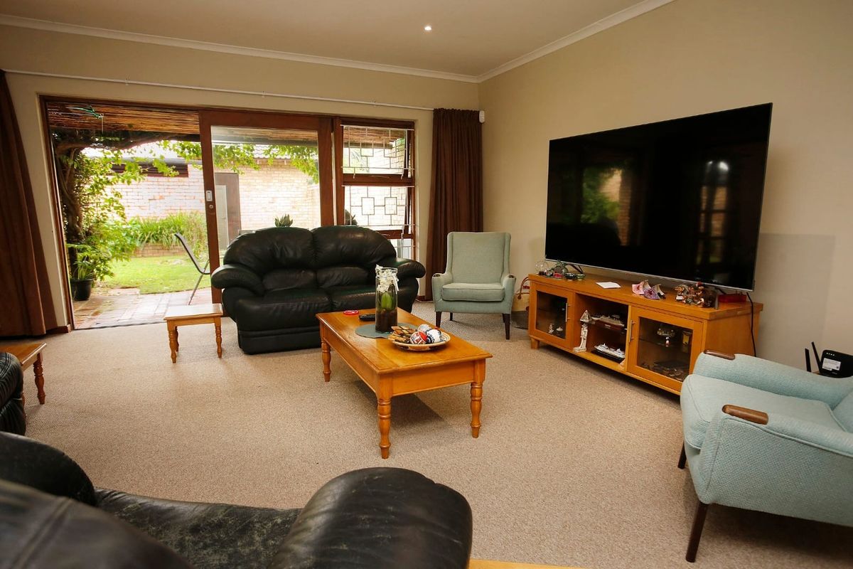 Spacious living room featuring neutral carpeting, recessed lighting, and large sliding glass doors providing direct access to the rear garden and patio area.