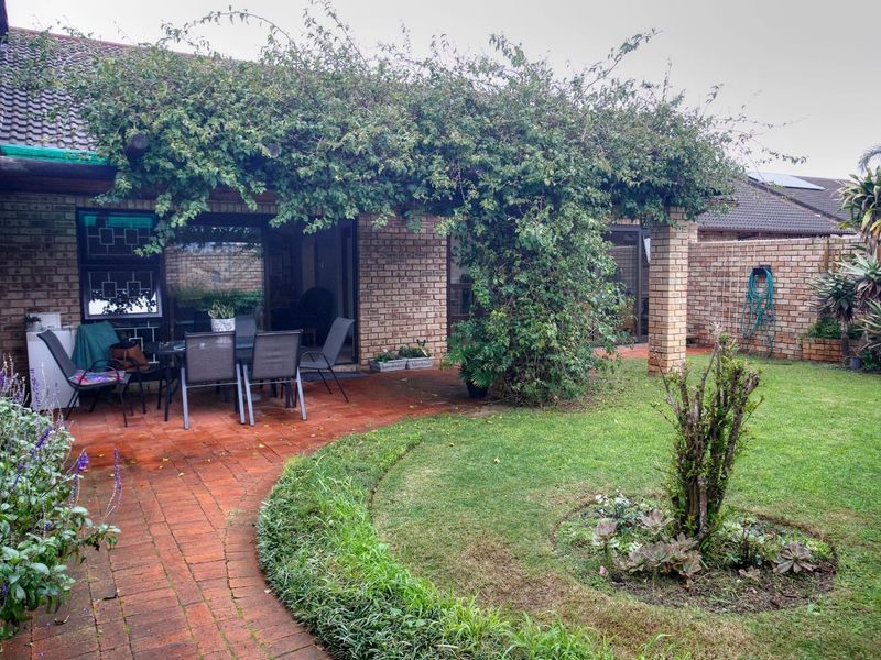 A private rear garden featuring a paved patio area with a pergola, established lawn, and perimeter brick walling.